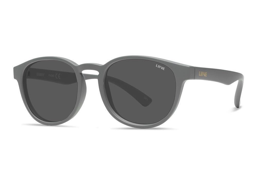 The Liive Bobby Sunglasses, featuring a round design in dark grey with a matte finish and dark lenses, are set against a white background. They have a sturdy polycarbonate frame for excellent UV protection, and the temples display "LINE" in elegant gold lettering.