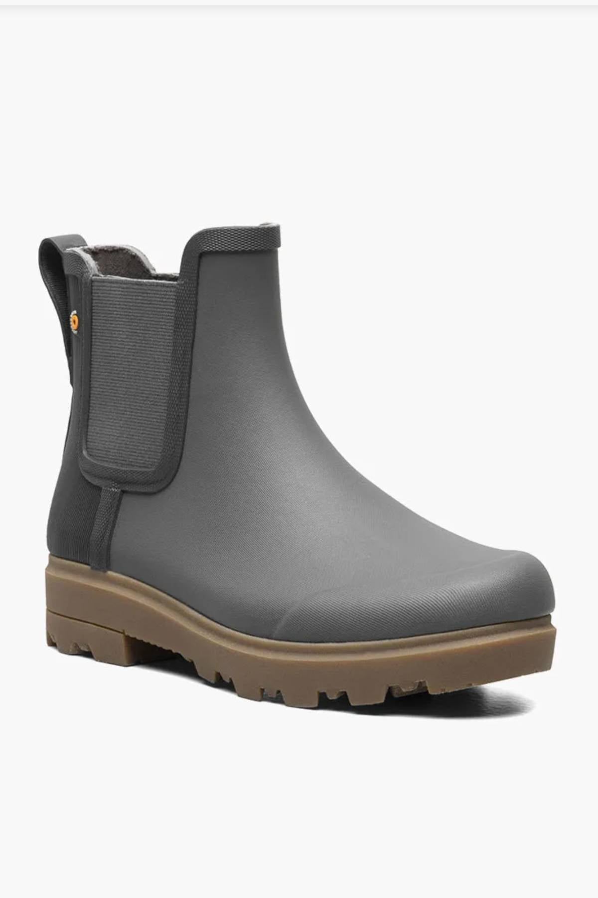 The BOGS Holly Chelsea Waterproof Boots are gray, ankle-height boots with elastic side panels, a back pull tab, a brown rugged rubber sole, and feature comfortable BLOOM Algae Footbeds.