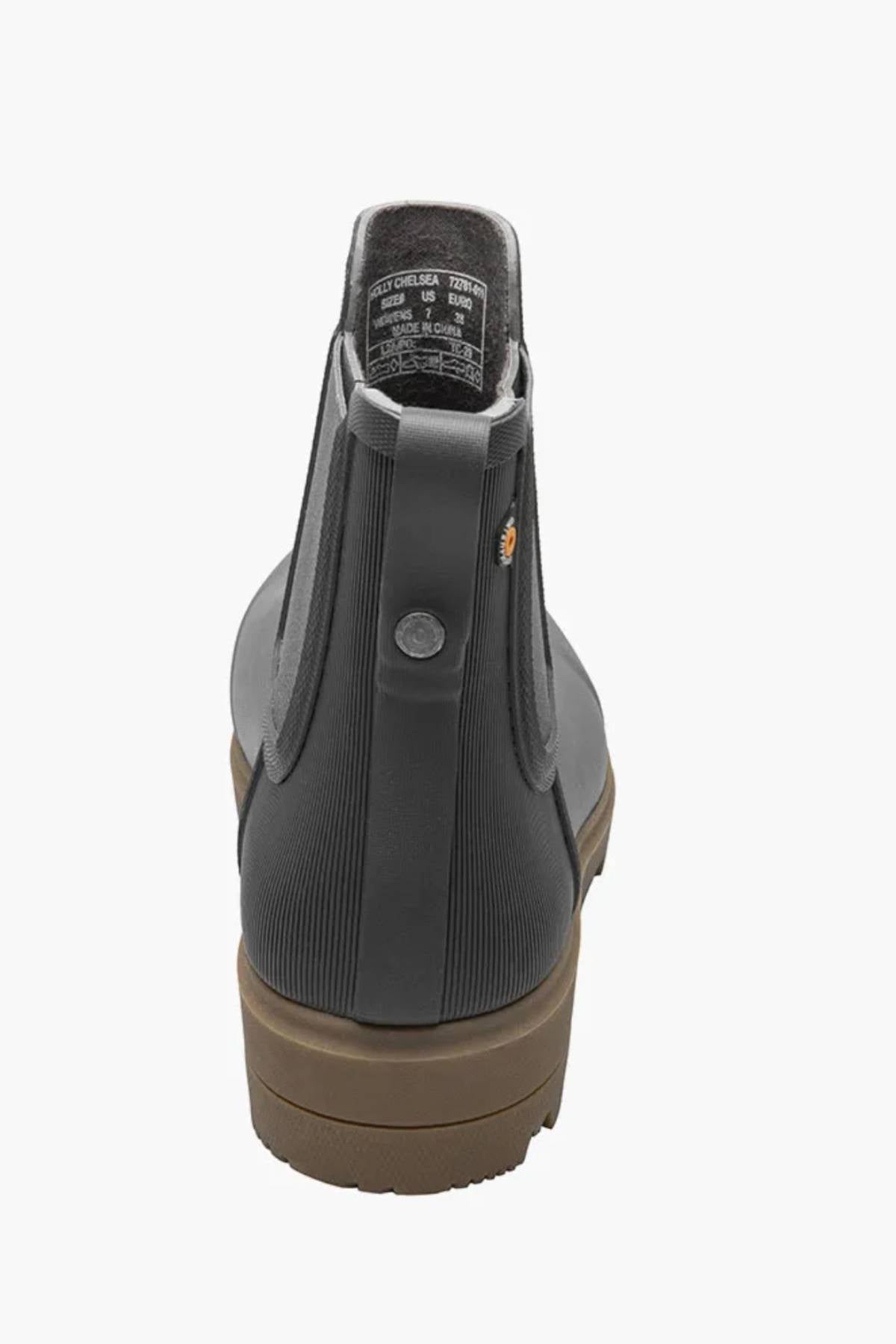 A close-up rear view of the BOGS Holly Chelsea Waterproof Boot in dark gray shows its brown sole, ribbed back texture, small round logo near the heel, and BLOOM Algae Footbeds for comfort.