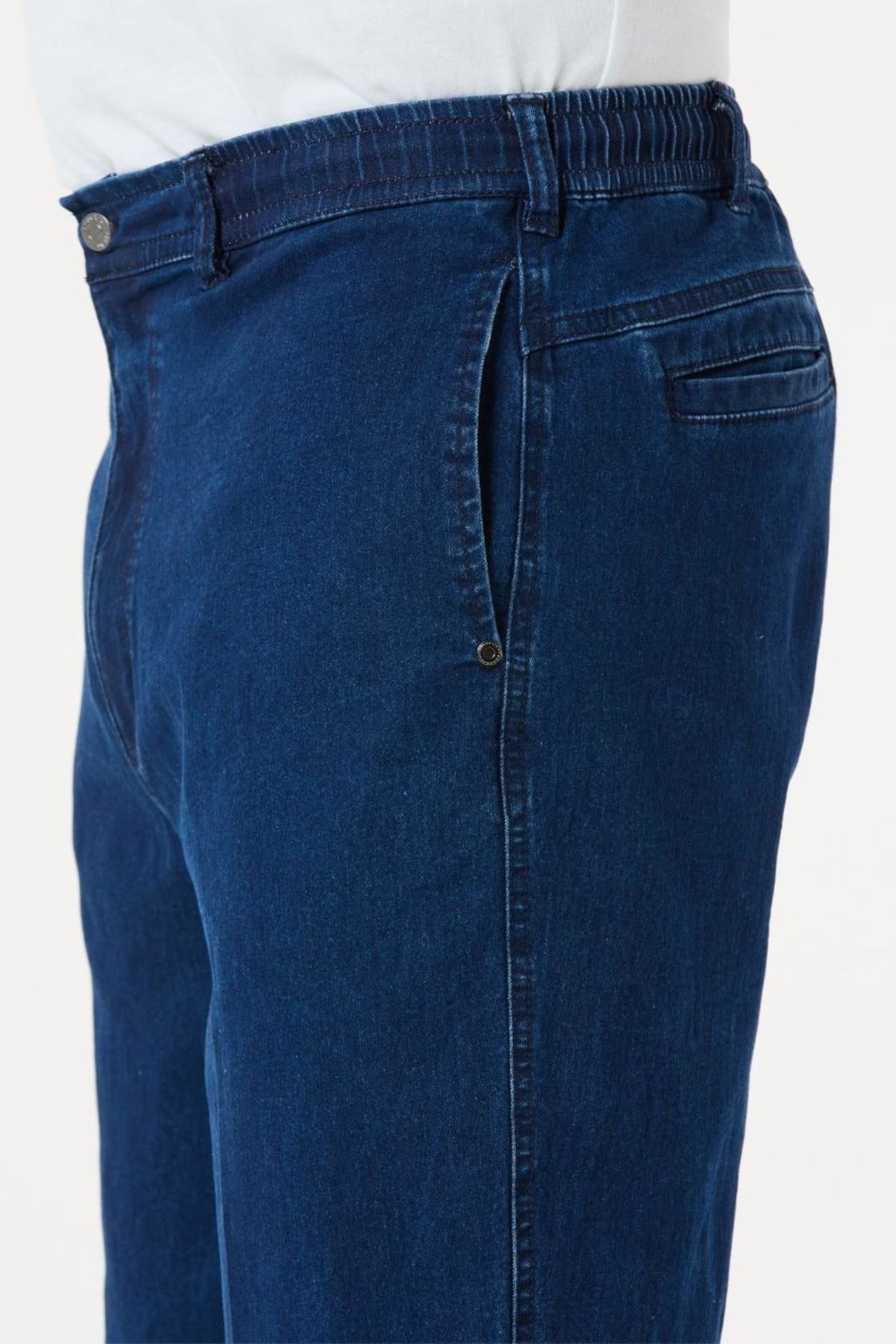 The photo depicts someone wearing the Breakaway Intense Denim Jean, characterized by its dark blue color and elastic waist. These straight-leg jeans include a buttoned pocket and visible stitching details. The individual pairs the jeans with a crisp white shirt.