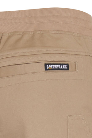 Close-up of the back pocket area on beige CAT Diesel Short 2.0 stretch ripstop shorts with an elastic waistband. A black and yellow "Caterpillar" label is sewn above the pocket, highlighting these durable work shorts.
