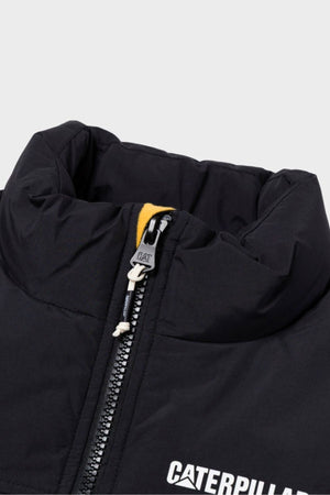 Close-up of the CAT Heavy Weight Insulated Puffer Jacket in black, featuring a visible zipper, yellow fabric detail underneath, and partially visible white "CATERPILLAR" lettering on the chest.