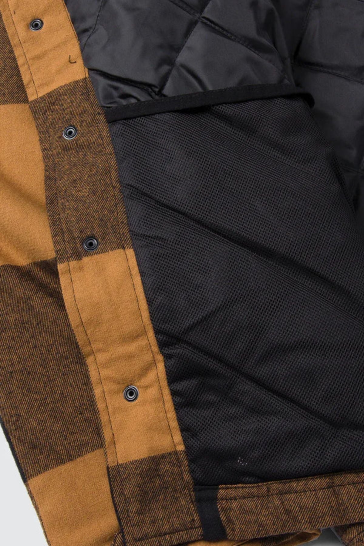 Close-up of the interior of the CAT Hooded Flannel Shirt Jacket, featuring black quilted lining with recycled insulation, a mesh inner pocket, and snap button closures along the front.