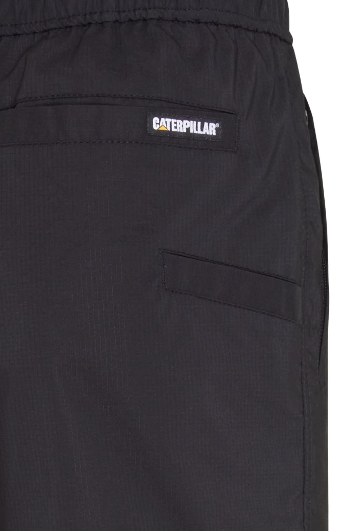 Close-up of CAT Hydraulic Short in black, featuring a Caterpillar logo patch above the front pocket, elastic waistband, and visible seam.