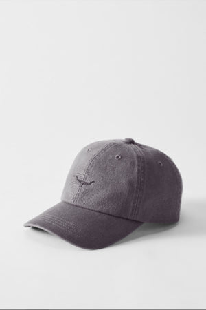 A gray RM Williams Mini Longhorn Twill Cap with an adjustable strap, curved brim, and visible stitching rests on a white surface. The front displays a small, subtle embroidered mini longhorn design.