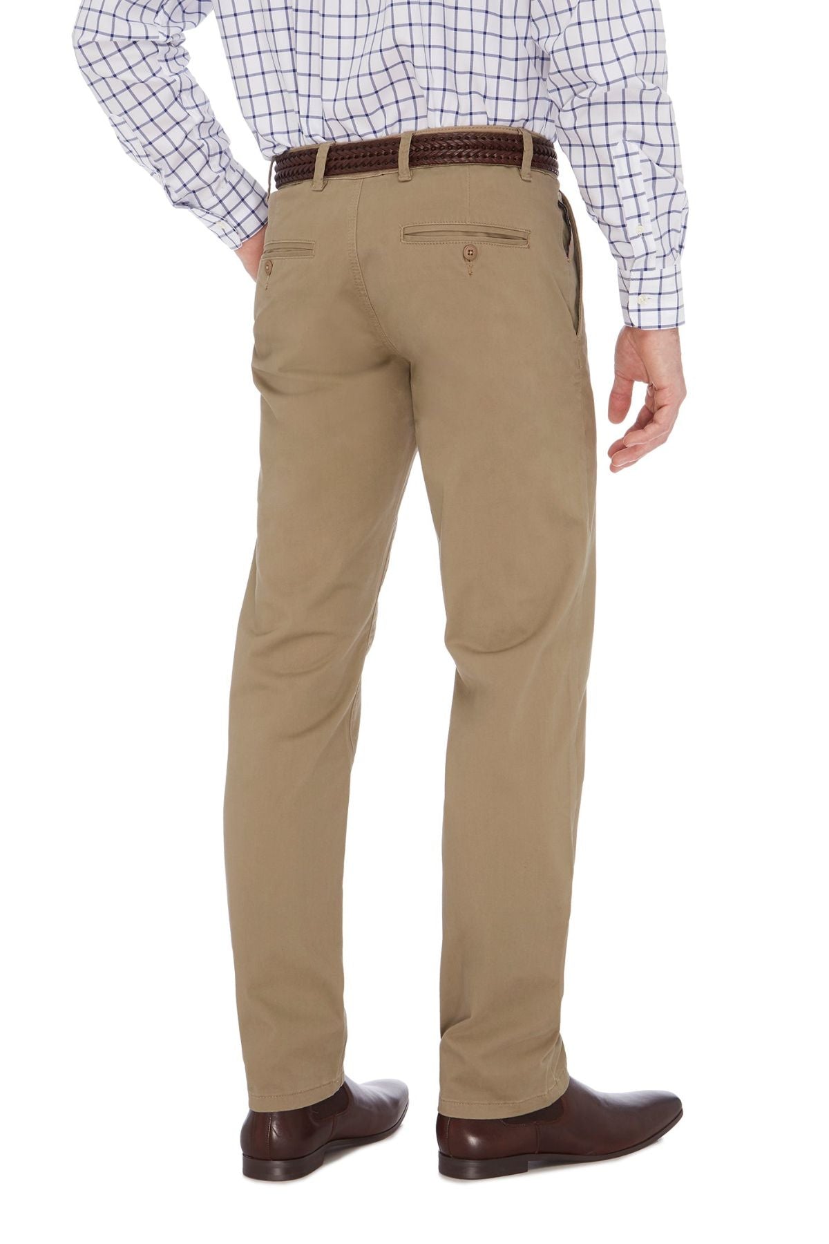 A man standing with his back to the camera, wearing a white checked shirt tucked into beige City Club Hammond Place Pants, secured with a brown belt. He is also wearing brown dress shoes. The background is plain white.