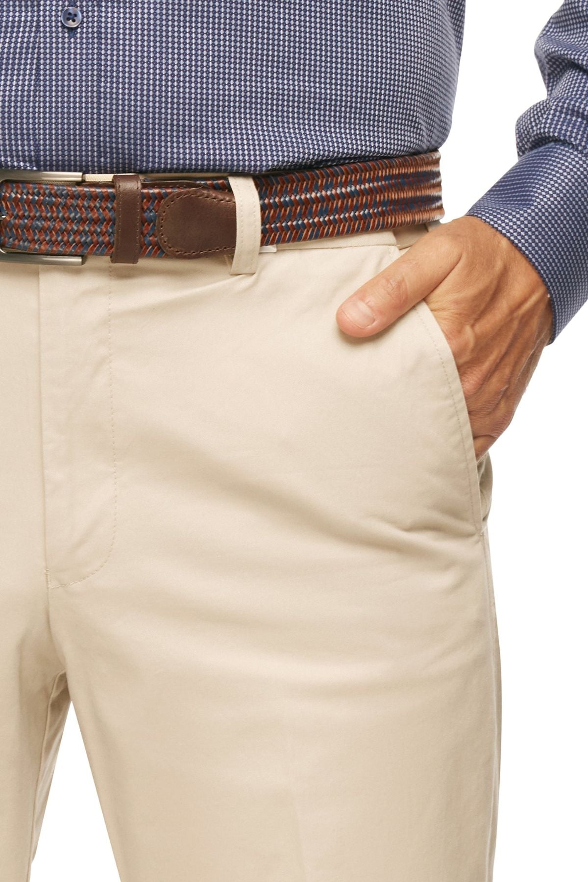 A person wearing beige City Club Mariner Harbour Pants featuring elasticated sides, paired with a brown woven belt adorned with blue and red designs, and a blue patterned shirt. The person has their right hand in their pocket.