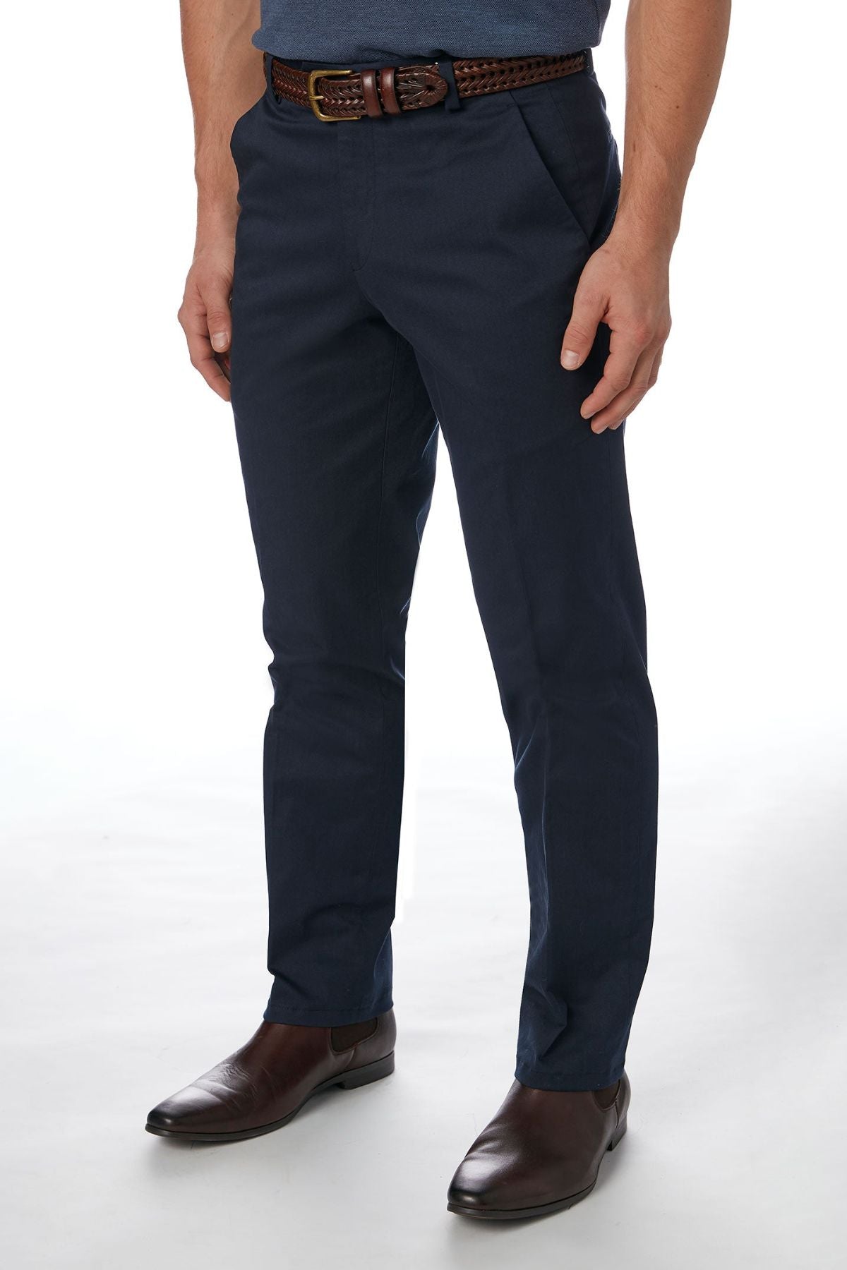 A person wearing the stylish and comfortable navy blue City Club Navigator 1770 Pant made from a blend of cotton and spandex, complemented by a brown woven belt and brown dress shoes, is standing against a plain white background. The image is cropped at the shoulders, focusing on the lower torso and legs.