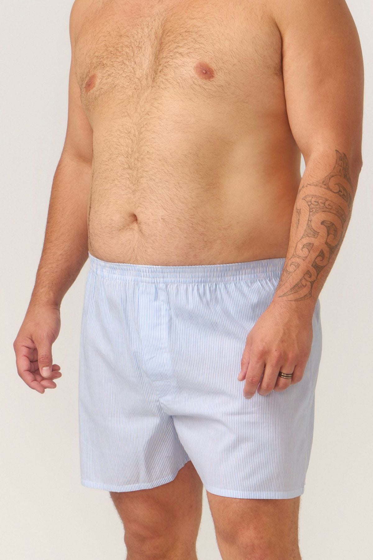 A man stands shirtless against a plain background, wearing Contare Cotton 2 Pack Check Boxer Shorts, revealing a tattoo on his right arm and a wedding ring on his left hand.
