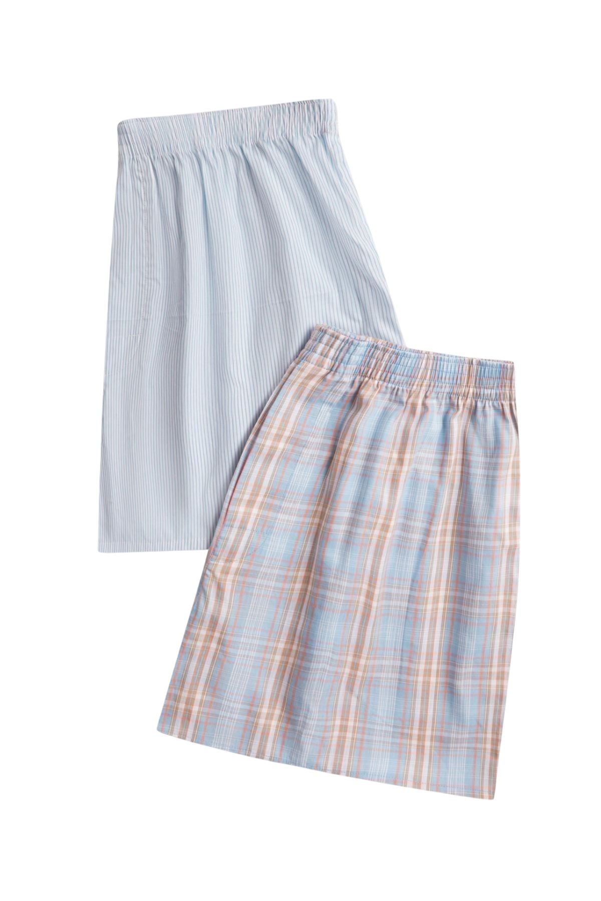 Two knee-length skirts, inspired by men's boxers, are made from soft cotton and styled with elastic waistbands—one in light blue with white stripes, the other in a pastel plaid—using fabric from the Contare Cotton 2 Pack Check Boxer Short.