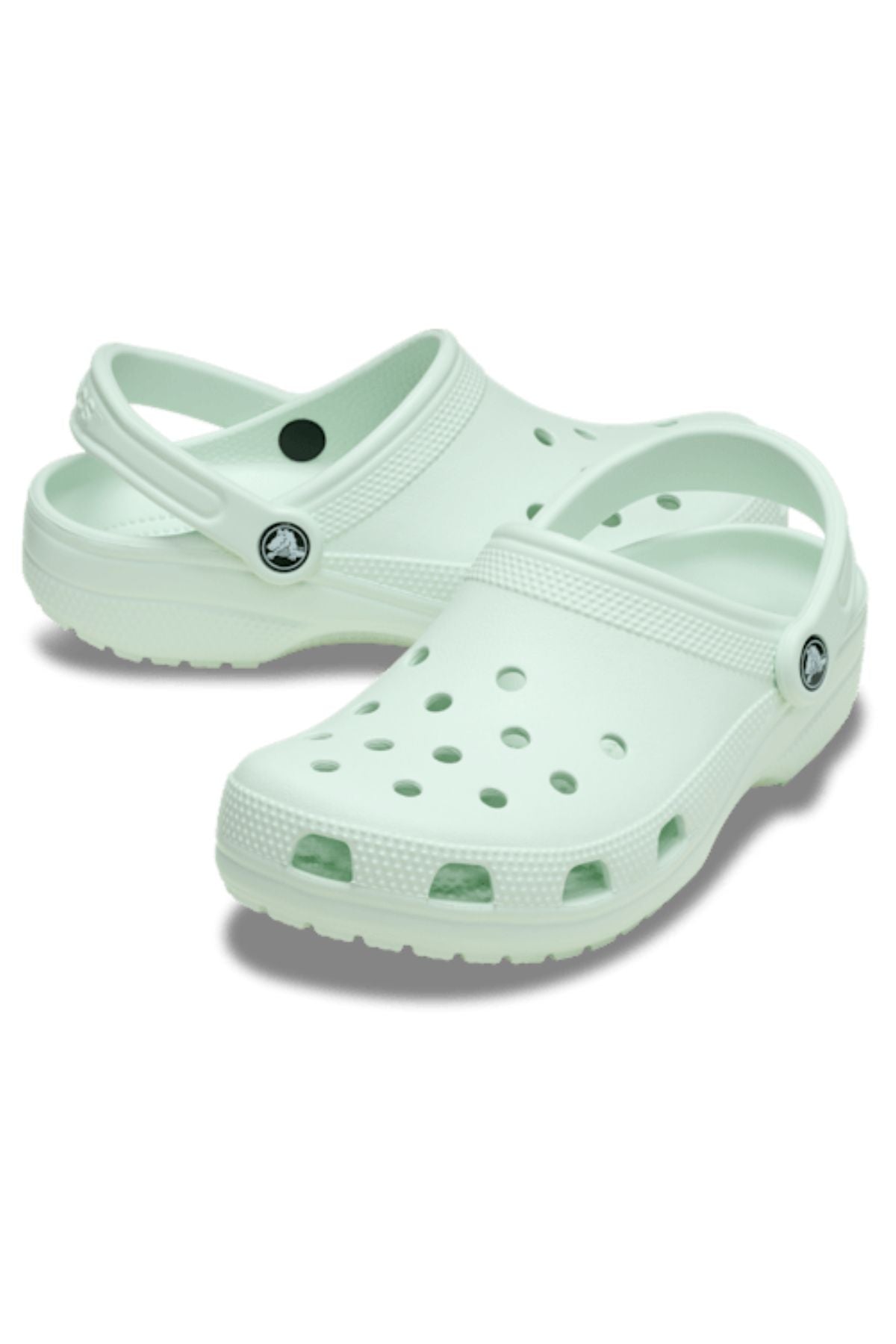 The Crocs Classic Clog in light mint green features lightweight, breathable construction with ventilation holes and adjustable heel straps, shown on a white background.