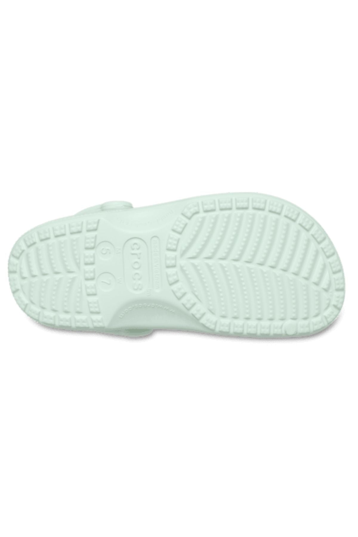 The image shows the light green sole of the Crocs Classic Clog, featuring a textured tread pattern for grip and displaying the Crocs logo with size marking "6 7" at the center.