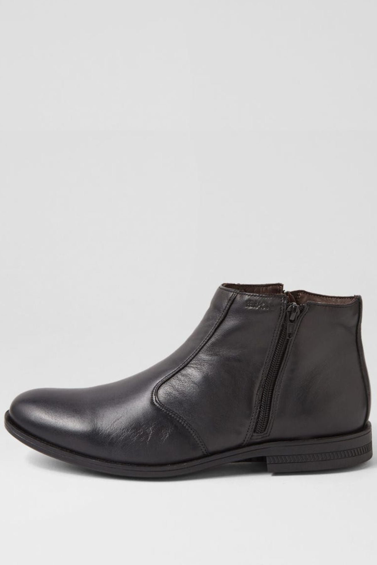 The Ferracini March Boot is a black genuine leather boot with a low heel, side zipper, and smooth finish, shown against a plain light gray background.
