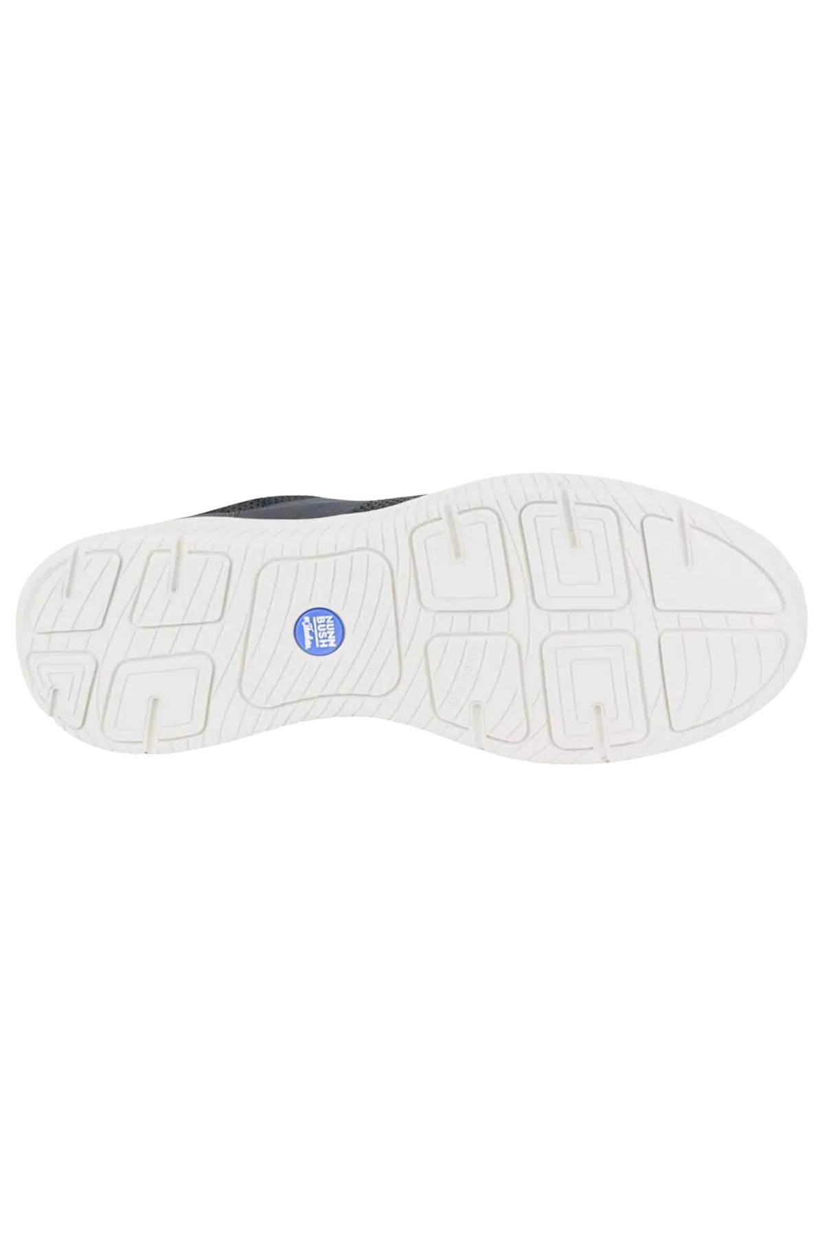 The image displays the white rubber sole of a Florsheim Kore City Pass Sneaker with a geometric tread, blue circular center logo, and a Comfort Gel heel pod for extra cushioning.