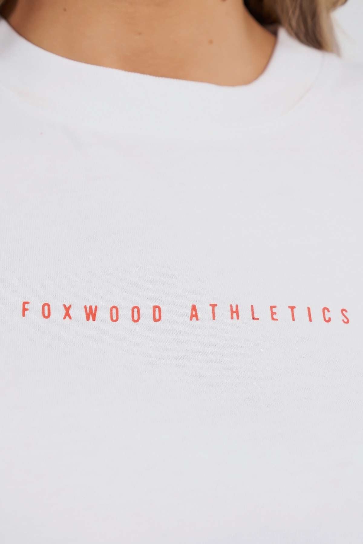 Close-up of the Foxwood Captain Tee, a white cotton T-shirt featuring "FOXWOOD ATHLETICS" in bold red uppercase letters across the chest—ideal for casual wear.