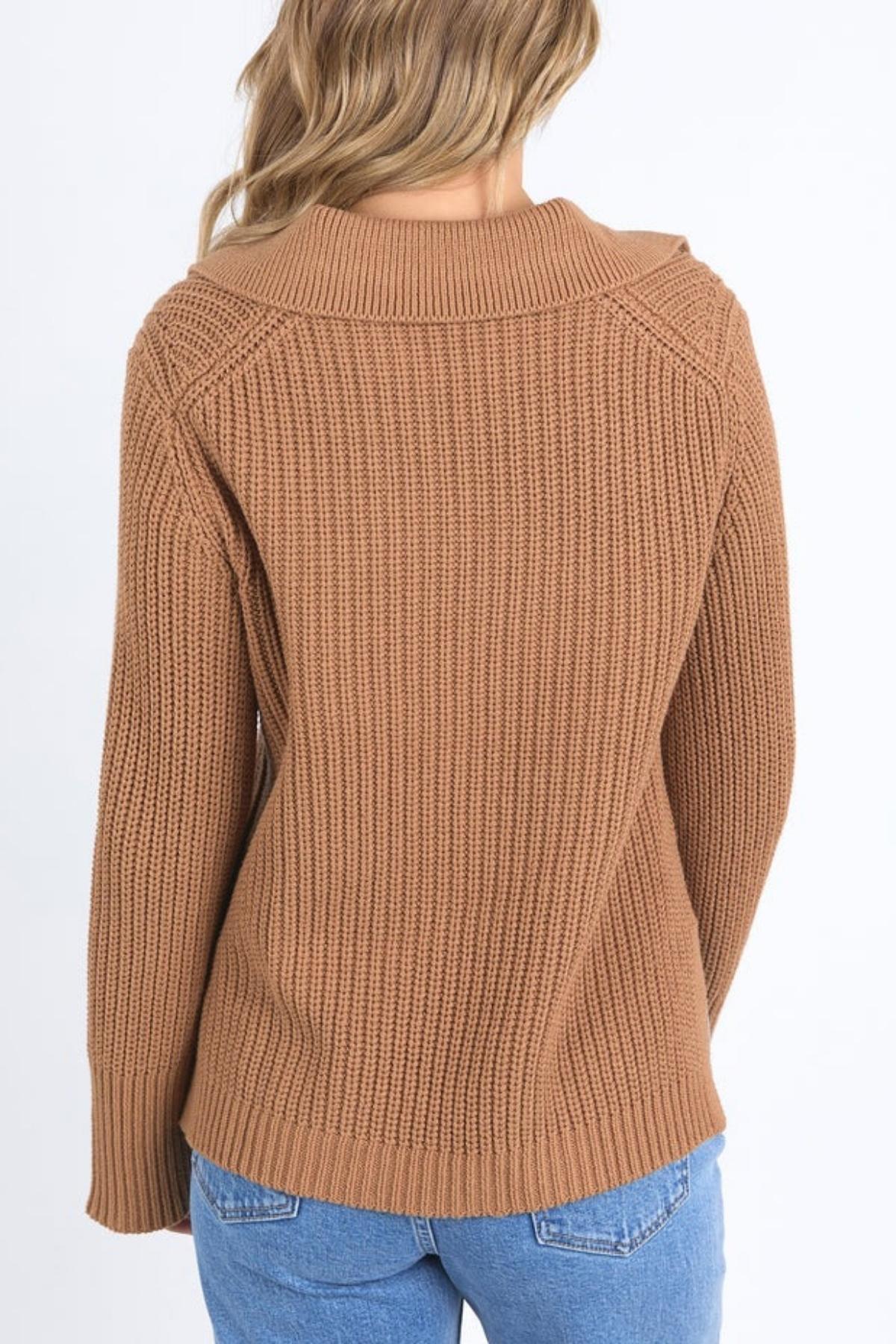 A person with wavy, light brown hair wears the relaxed fit Foxwood Carlton Knit in brown with blue jeans, photographed from the back against a plain white background for an effortless, comfortable look.