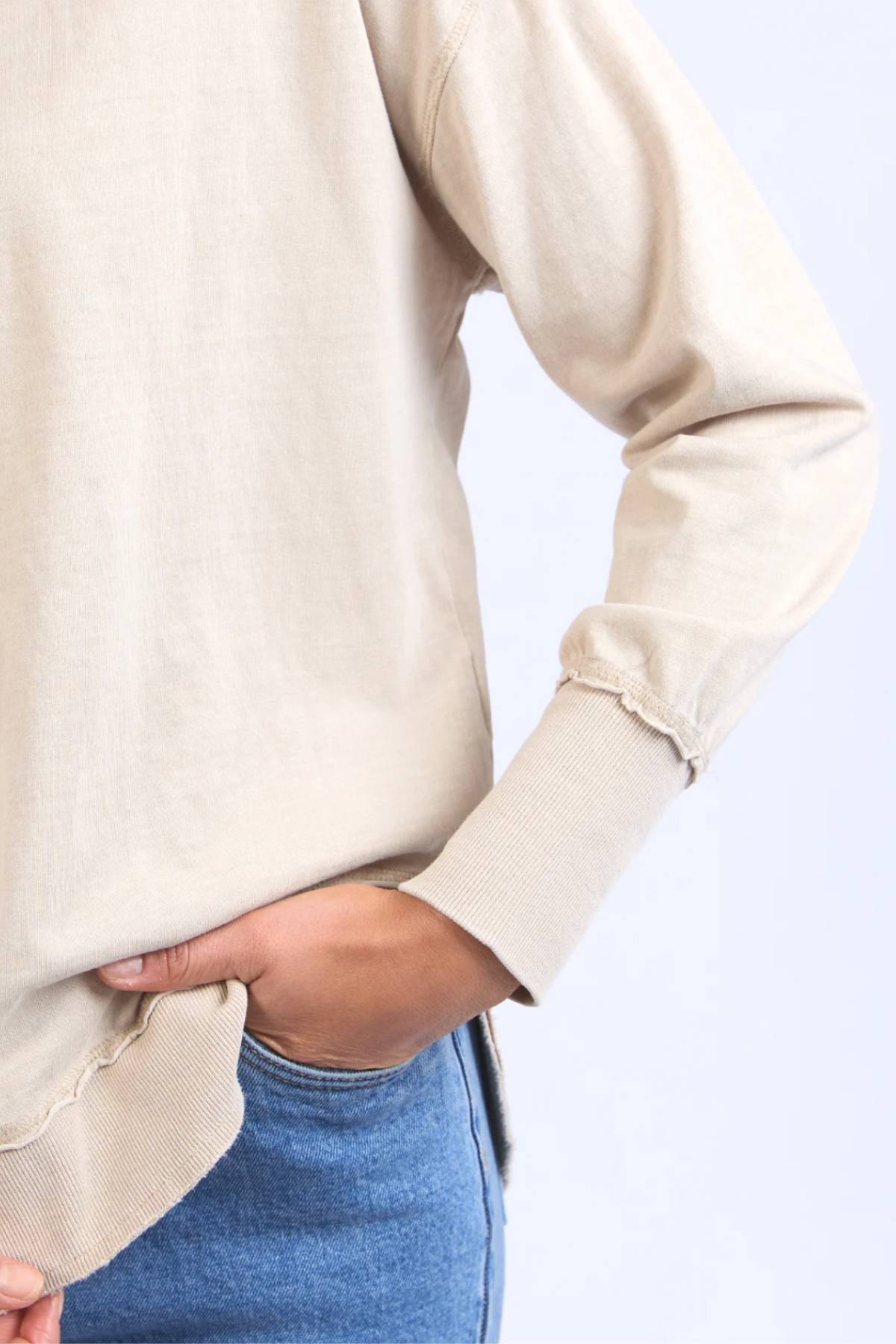 A person models the Foxwood Farrah Long Sleeve top with blue jeans, posing waist-up against a light background, one hand in their pocket.