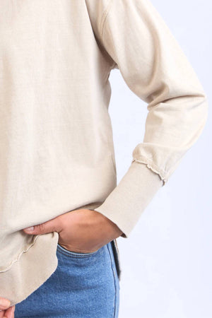 A person models the Foxwood Farrah Long Sleeve top with blue jeans, posing waist-up against a light background, one hand in their pocket.