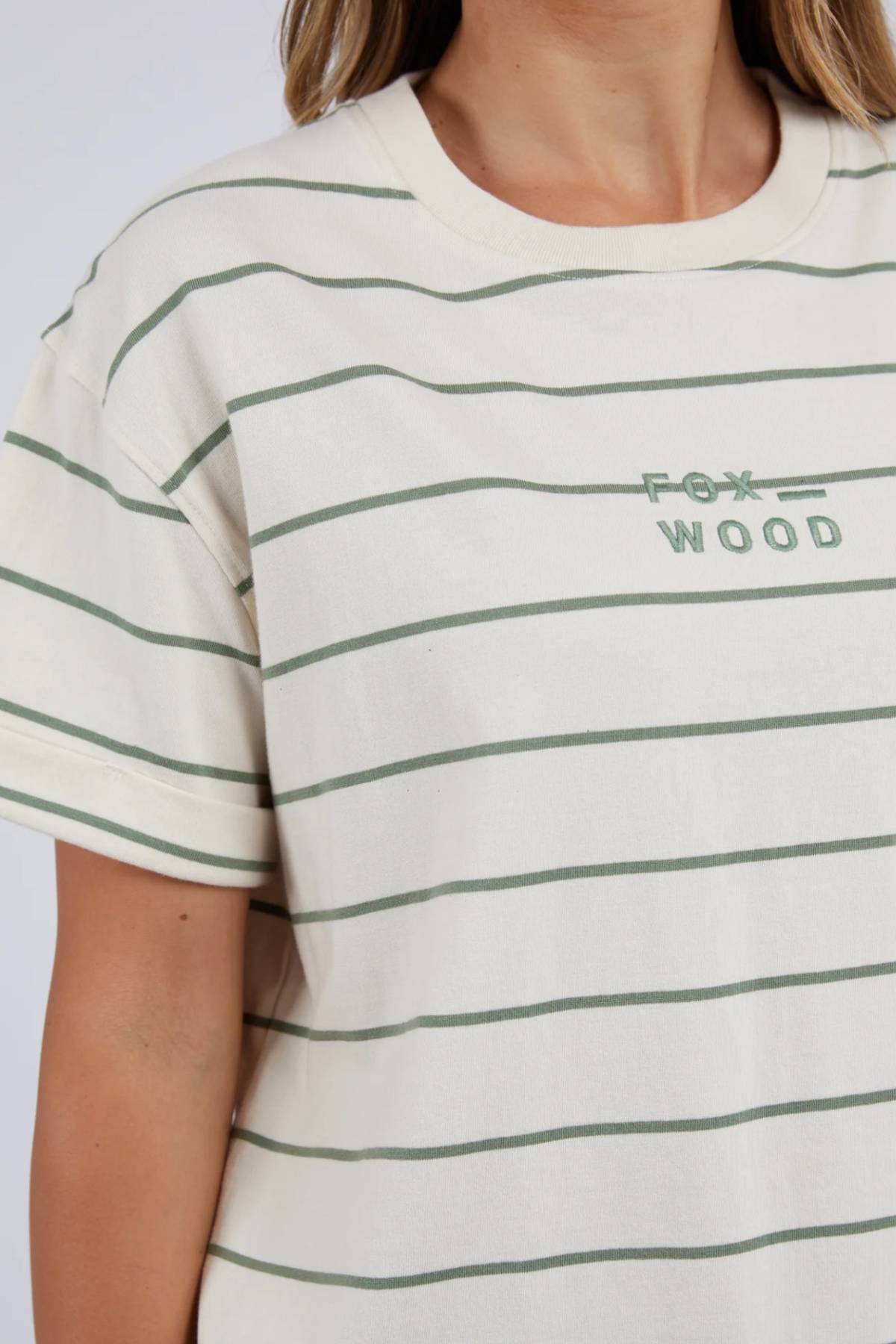 Wearing a chic Foxwood Huntleigh Stripe Tee, this stylish 100% cotton shirt features green horizontal stripes with "Fox Wood" elegantly embroidered. Its short sleeves and cream-colored backdrop stand out against the plain light background.