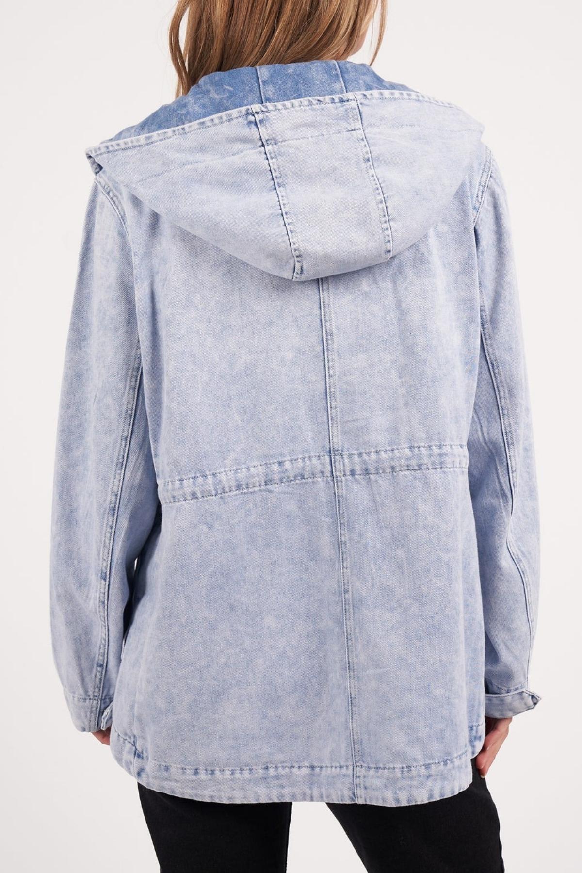 A person is seen from the back wearing a light blue Foxwood Kingston Anorak in vintage washed rigid denim, featuring visible stitching, a loose fit, an adjustable waist cord, and a hood worn down with hands at their sides.