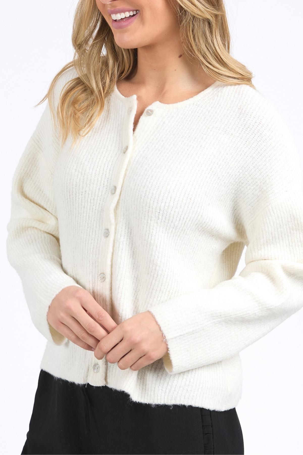 A woman wearing the Foxwood Murphy Knit Cardi in white with a relaxed fit and black pants, smiling with her hair down against a plain white background.