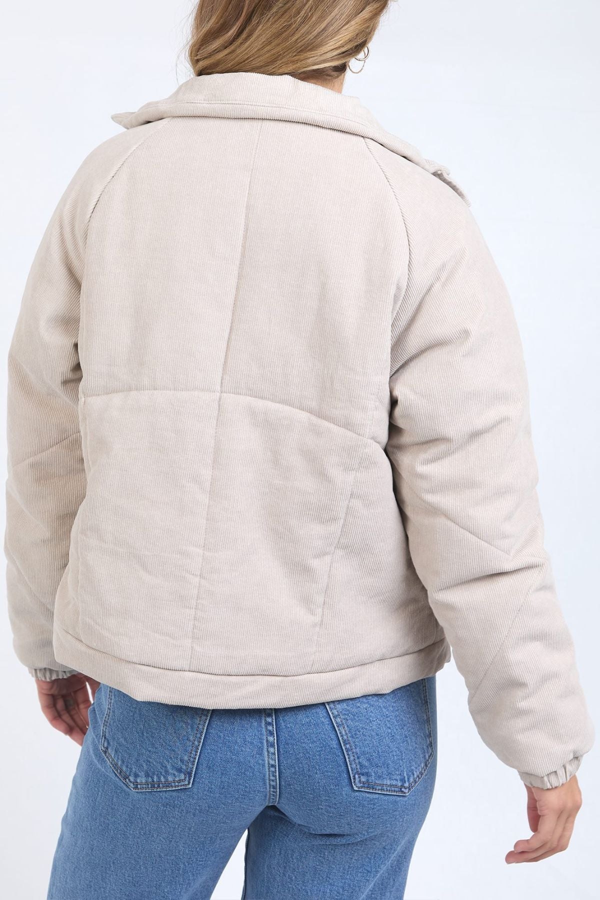 Someone wearing the Foxwood Rosalee Cord Jacket in light beige, made of 100% cotton, paired with blue jeans, shown from the back against a plain white background.