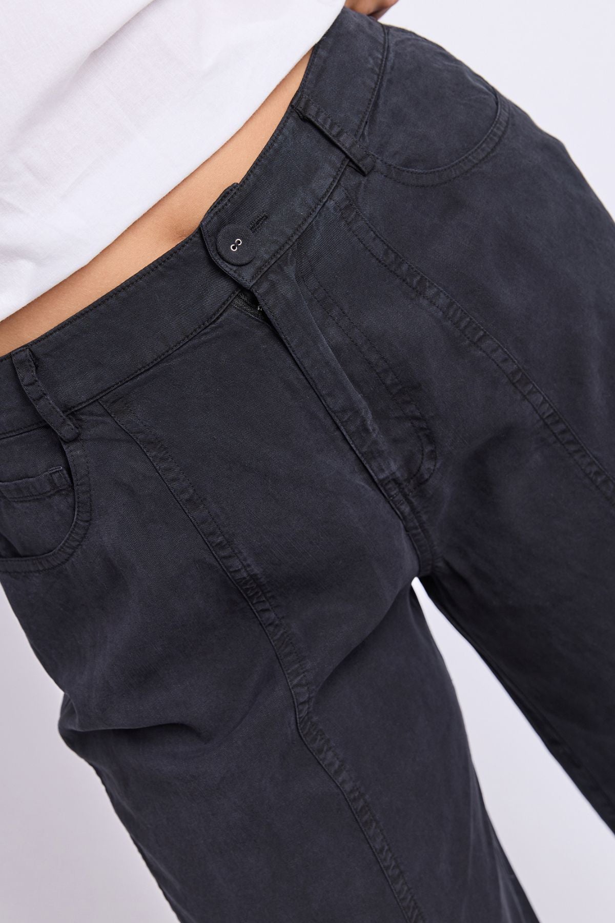 Close-up of a person wearing the Foxwood Roy Pant in dark gray paired with a white shirt, focusing on the waistband and upper section of the pants.