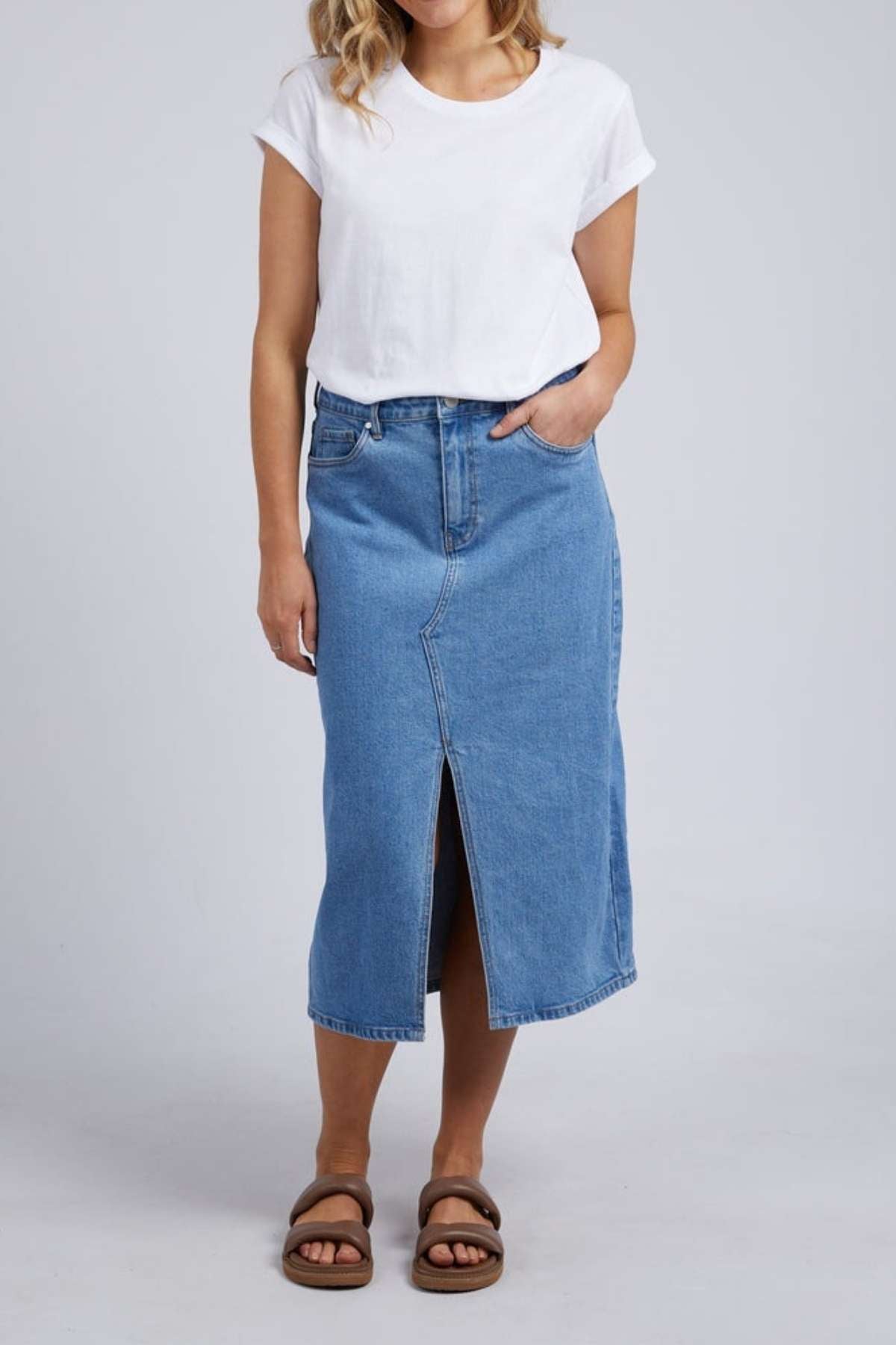 A person in a white t-shirt and brown sandals is wearing a Foxwood Scout Midi Skirt featuring a front slit, standing against a plain backdrop.