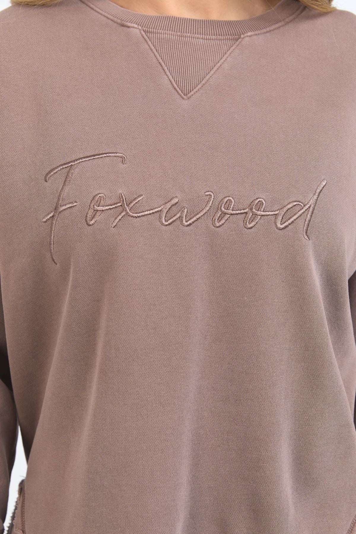 A close-up of the Foxwood Signature Crew, a 100% cotton crewneck sweater in mauve with "Foxwood" embroidered in cursive on the chest.
