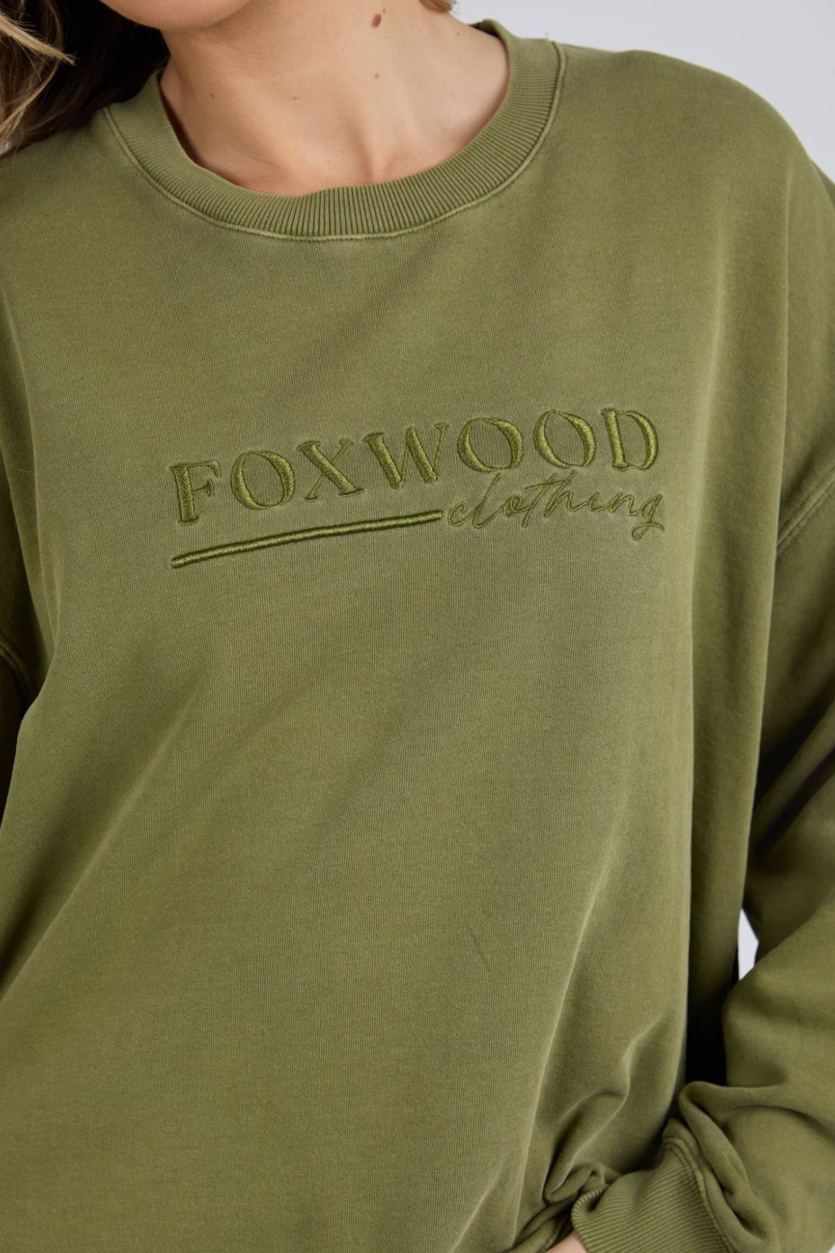 Wearing the Foxwood Trademark Crew, an olive green sweatshirt crafted from unbrushed cotton fleece and featuring “FOXWOOD clothing” embroidery on the front, adds casual style to any wardrobe.