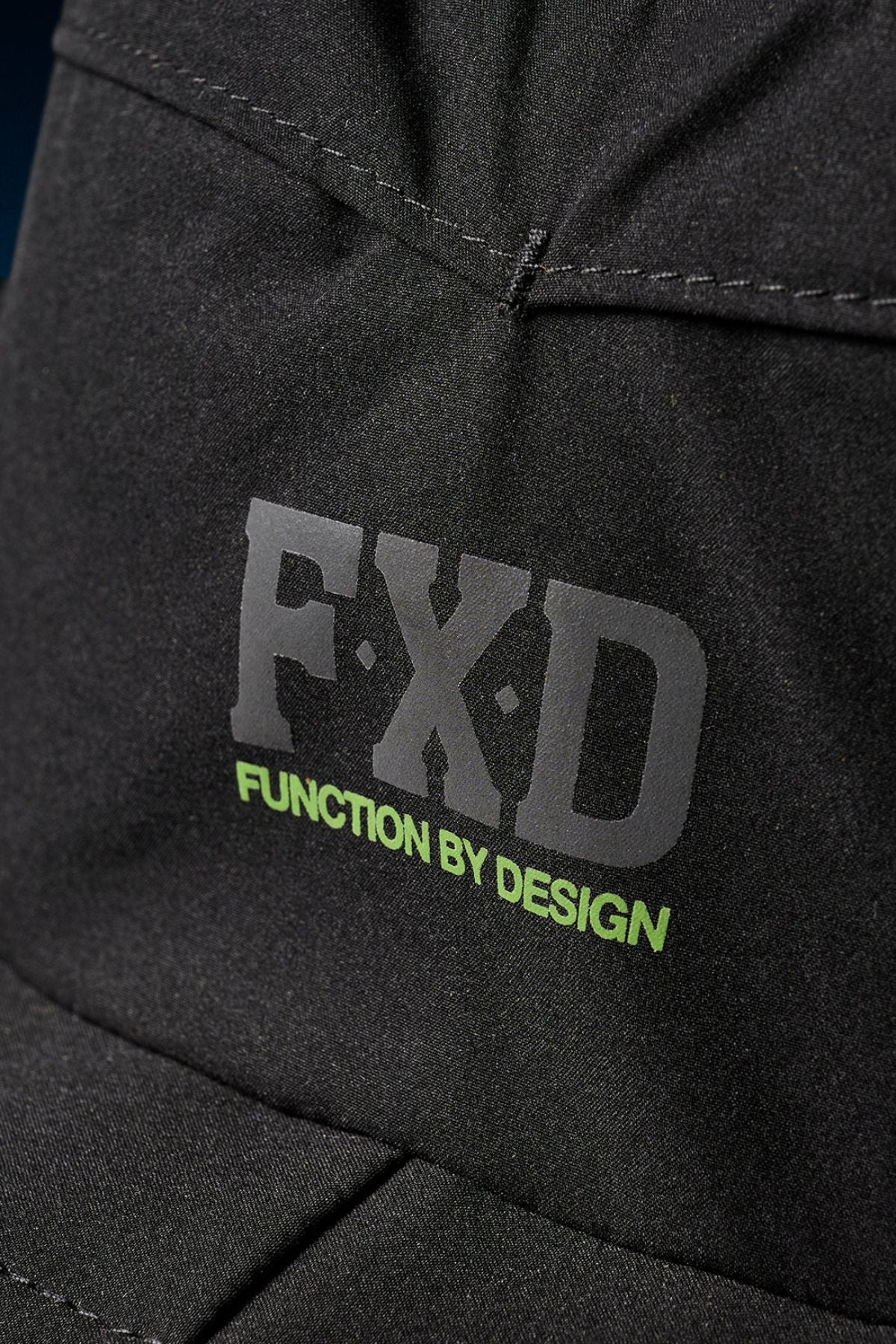 Close-up of the FXD CP-14 Boonie Hat’s black fabric, featuring "FXD" in large grey letters and "FUNCTION BY DESIGN" in smaller green print—perfect for sun protection during outdoor work.