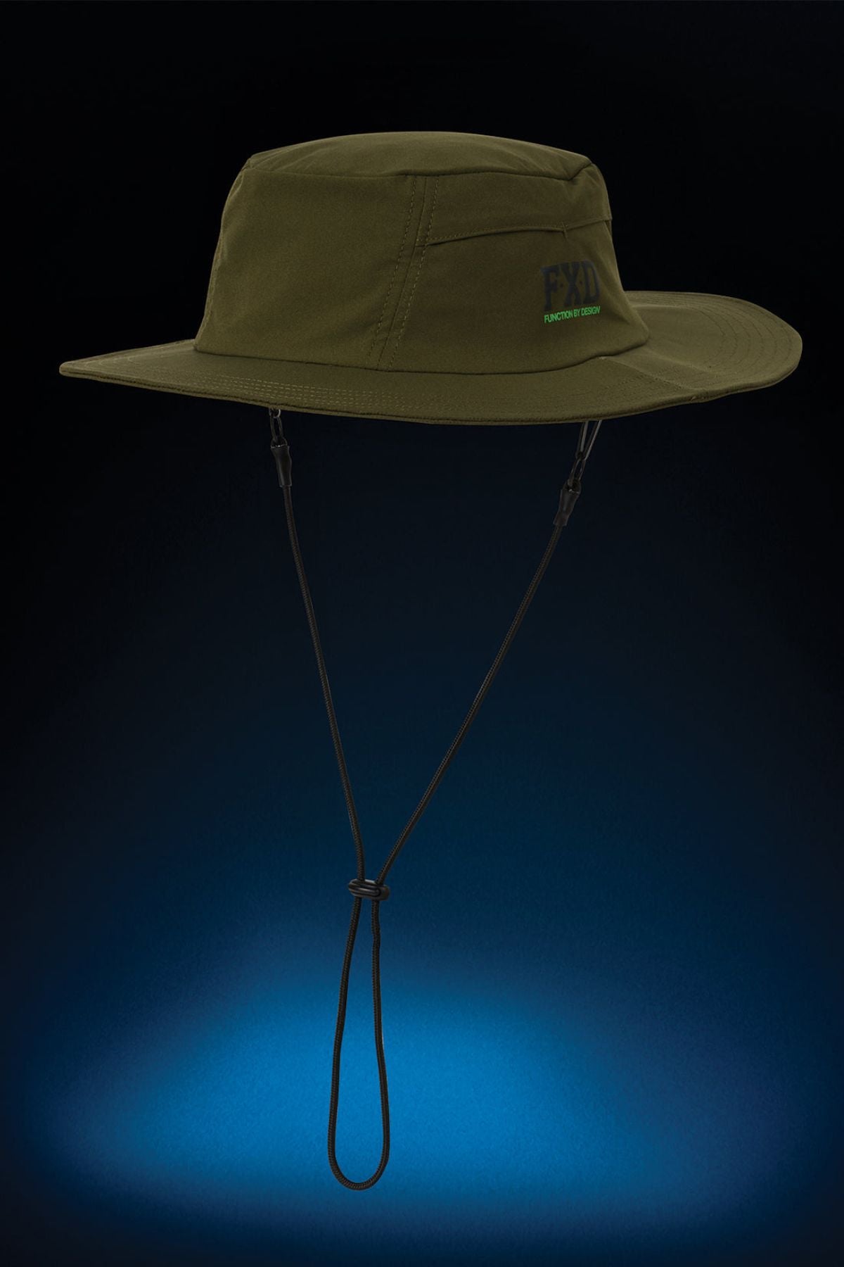 The FXD CP-14 Boonie Hat in olive green features side vents, a chin strap, and "FXD" embroidery on the front—ideal for sun protection during outdoor work. Shown against a dark background with a blue spotlight below.