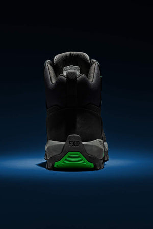 The FXD WB-3 Work Boot, displayed from the rear, rests on a dark blue surface against a black backdrop. It is made from premium leather and showcases a green accent on the sole, embodying a rugged design suitable for outdoor use.