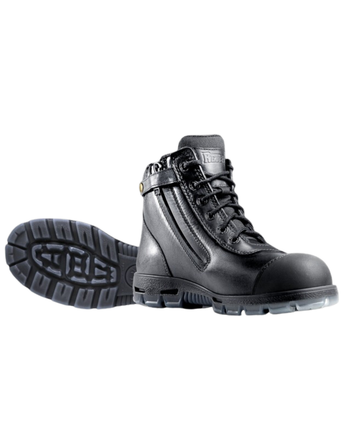 The Redback Cobar Safety Toe Zip Boots in black feature lace-up fronts, thick rugged soles with visible tread pattern, a shock-absorbing midsole for comfort, and a safety toe. One boot stands upright while the other lies on its side.