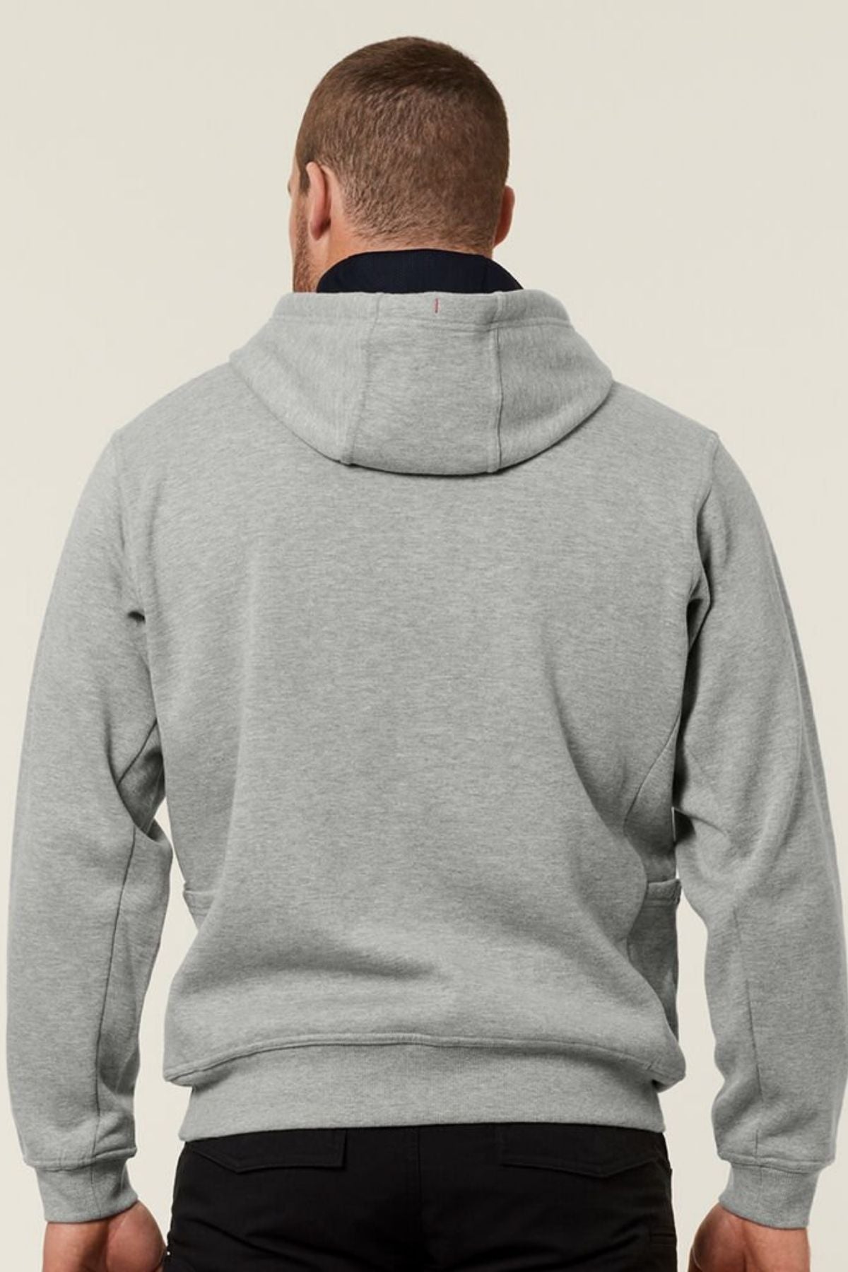 A person is seen from the back wearing a light gray Hard Yakka Plain Fleece Hoodie and black pants against a plain light background.