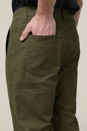 Wearing Hard Yakka Heritage Carpenters Pant, a person poses with one hand in the back pocket, showcasing the stretch canvas work pants’ stitching and pocket details against a plain backdrop.