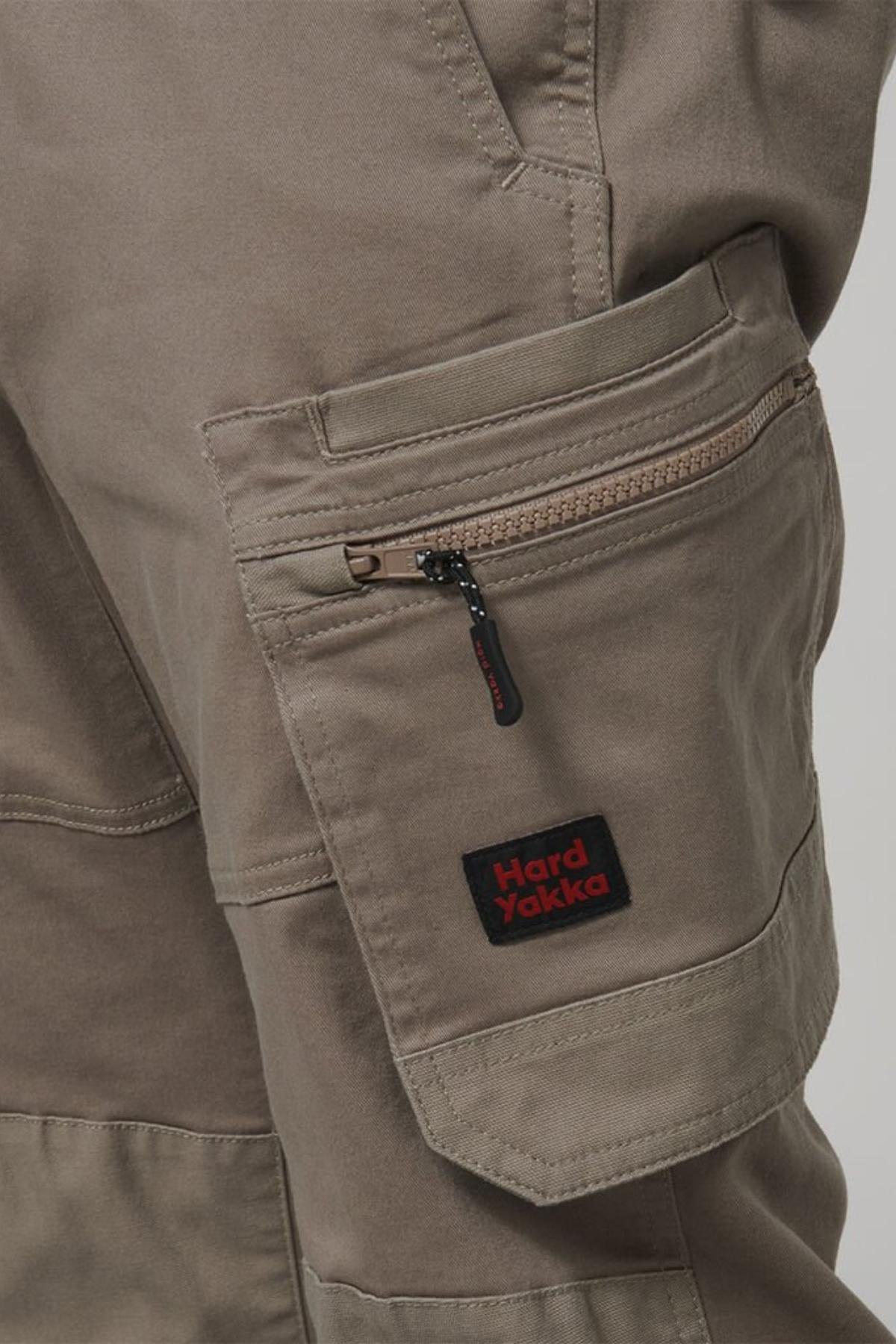 Close-up of the Hard Yakka Tough Maxx Pant’s brown cargo pocket, featuring a visible zipper, detailed stitching, multiple pockets, and a black-and-red Hard Yakka label on the pocket flap.