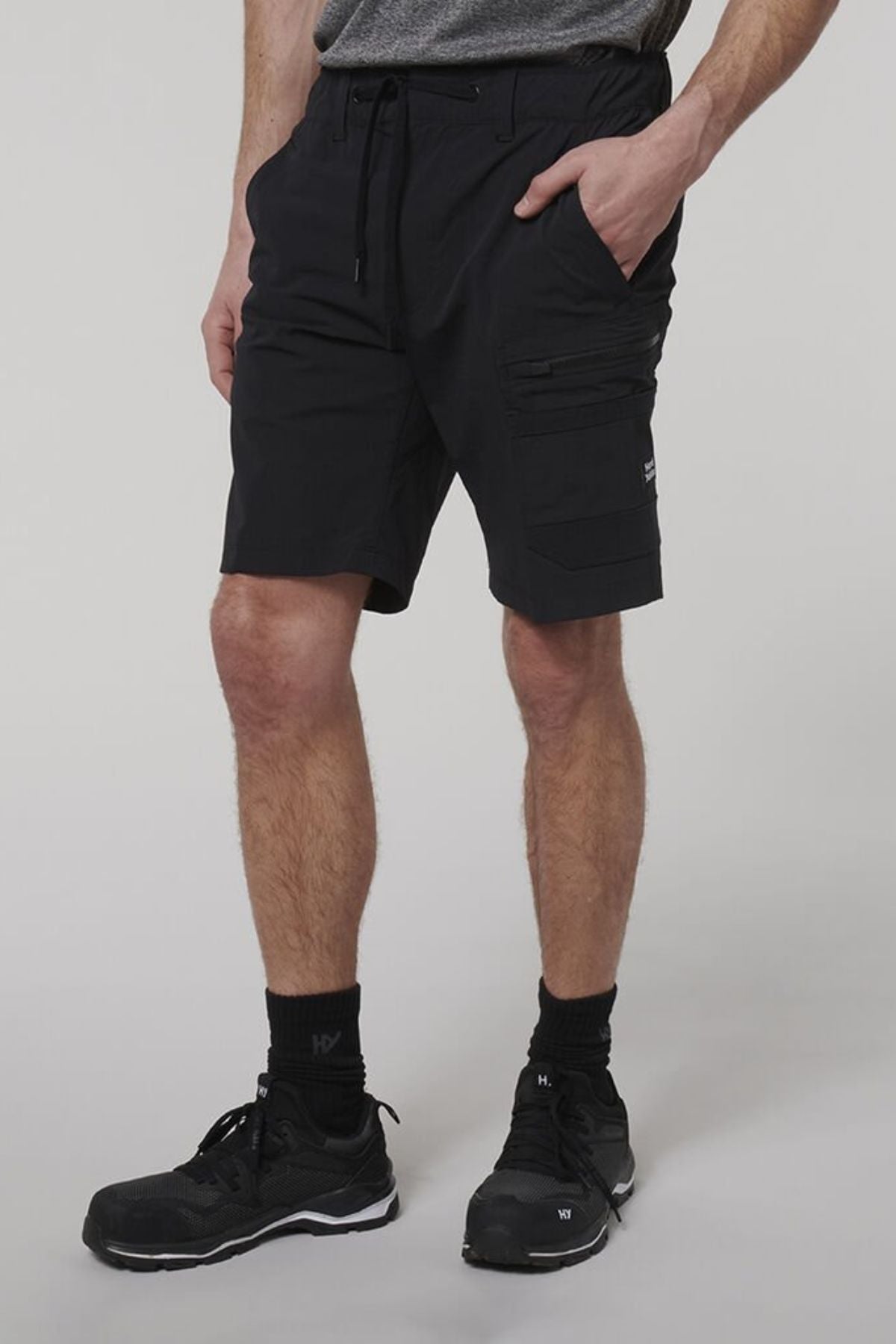 A man wearing Hard Yakka X Range Mid Shorts, crafted from durable black Cordura nylon.