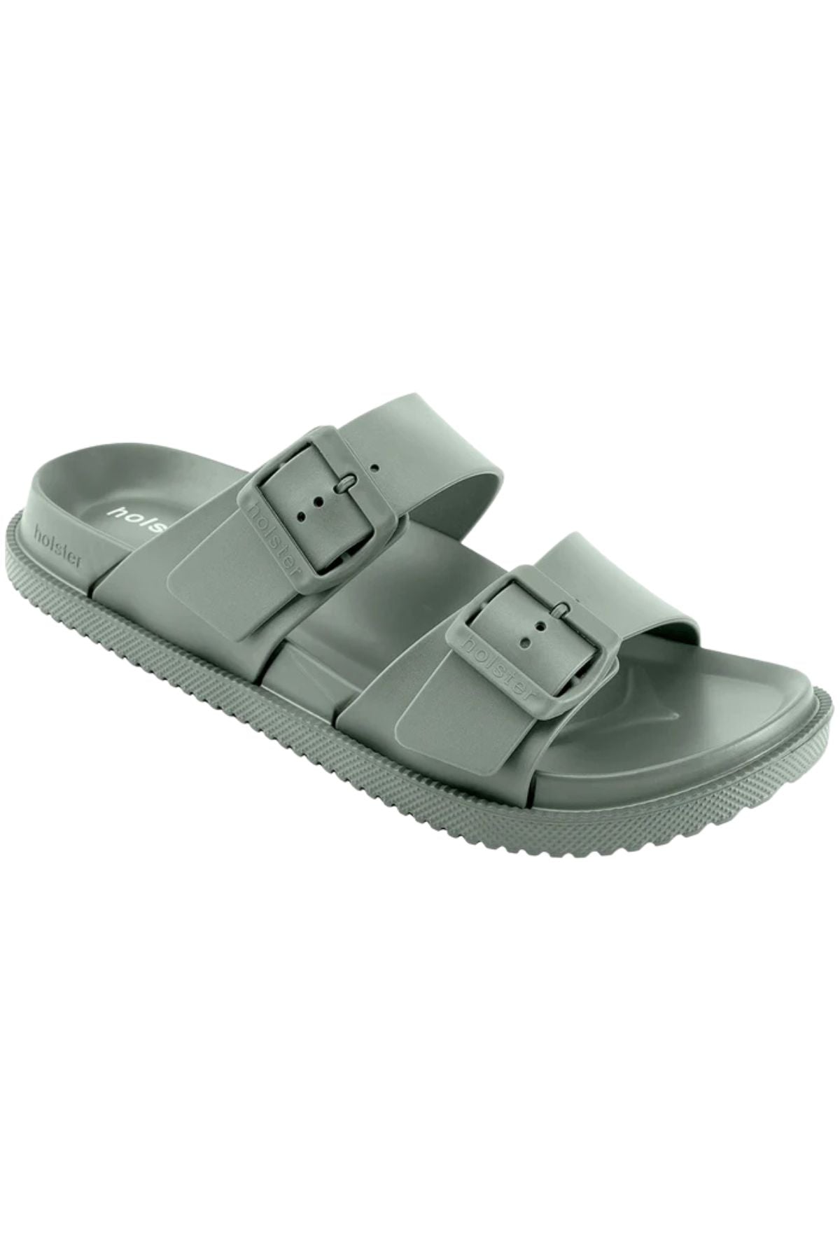 The Holster Soleseeker is a light gray slide sandal featuring two adjustable buckle straps, vegan materials, and a textured sole for enhanced arch support, displayed against a white background.