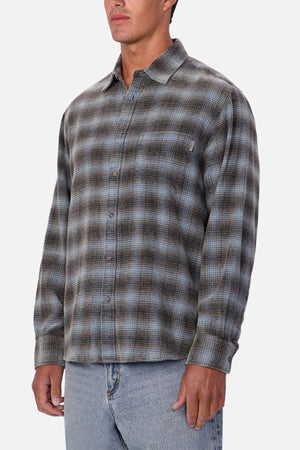 A person wearing the Industrie Durango Long Sleeve Shirt in gray and blue plaid with light blue jeans stands against a plain white background—a classic wardrobe essential.