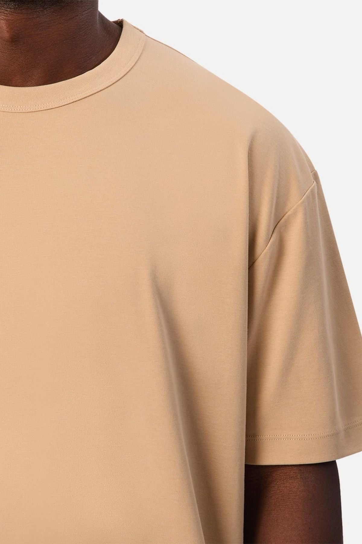 Close-up of a person wearing the Industrie Luxe Del Sur Tee, a relaxed-fit T-shirt crafted from 100% cotton, against a white background, with only the upper chest, shoulder, and part of the neck and arm visible.