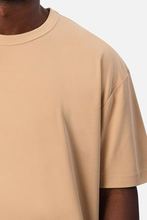 Close-up of a person wearing the Industrie Luxe Del Sur Tee, a relaxed-fit T-shirt crafted from 100% cotton, against a white background, with only the upper chest, shoulder, and part of the neck and arm visible.