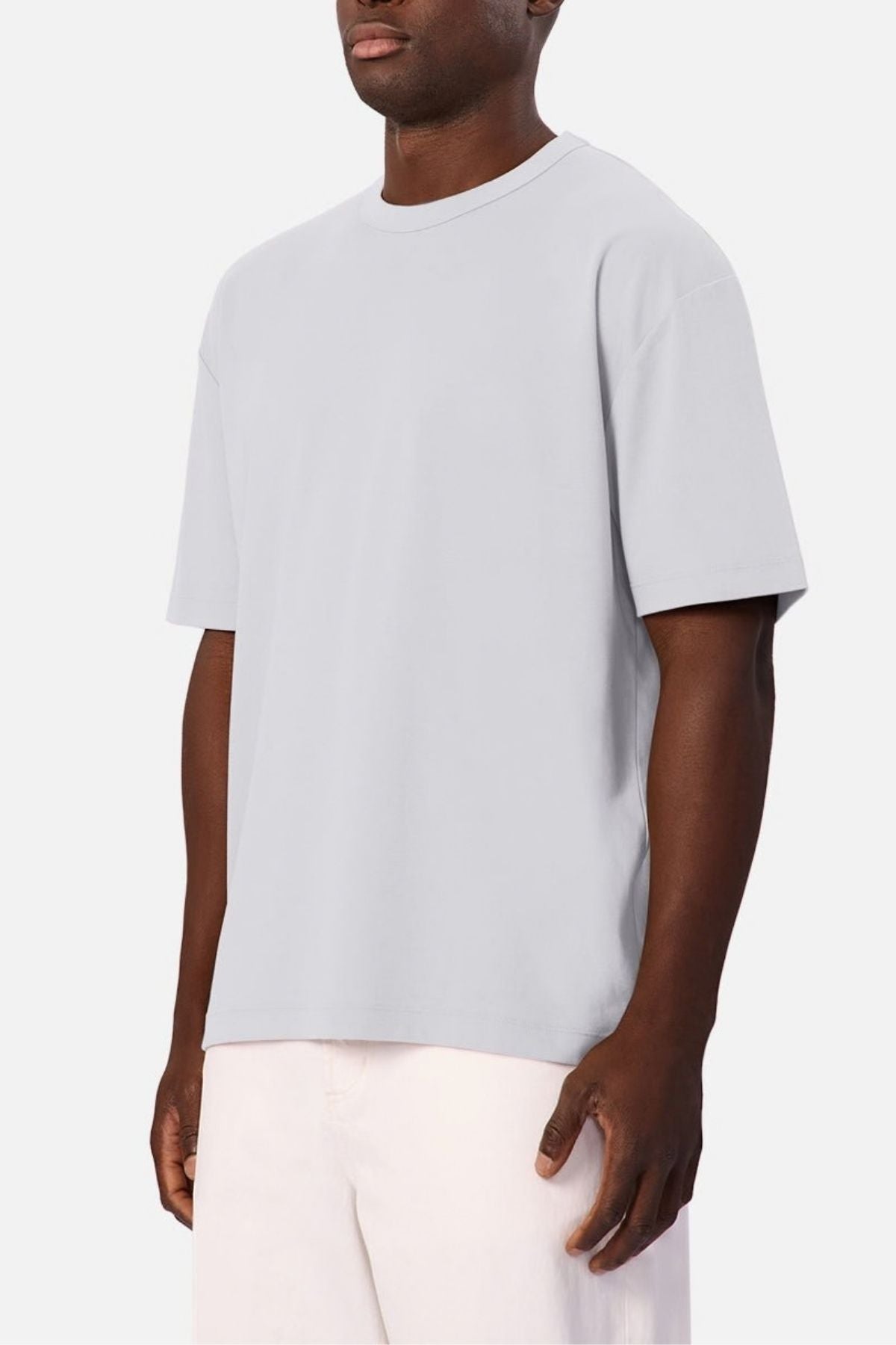 Wearing the Industrie Luxe Del Sur Tee, a relaxed-fit shirt made from 100% cotton, and light-colored shorts, a man stands against a plain white background.