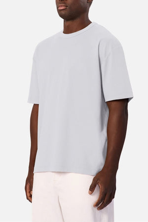 Wearing the Industrie Luxe Del Sur Tee, a relaxed-fit shirt made from 100% cotton, and light-colored shorts, a man stands against a plain white background.