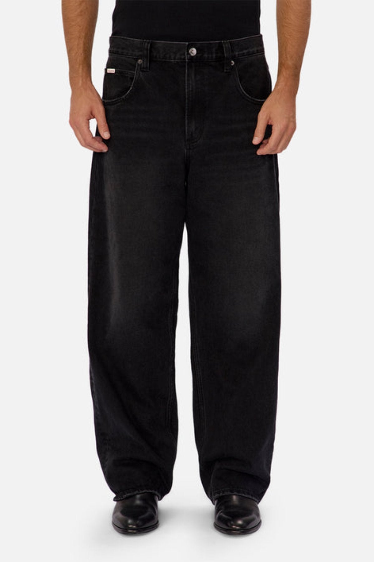 A person models the Industrie The 80's Jean—vintage-inspired, black durable denim—paired with black shoes, standing facing forward against a plain light gray background. Only the lower torso and legs are shown.