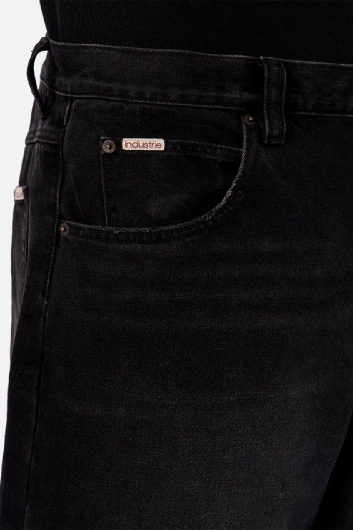 Close-up of the upper section of Industrie The 80’s Jean in black, durable denim with a visible front pocket and "Industrie" label above it. The wearer has paired these vintage-inspired jeans with a tucked-in black top.
