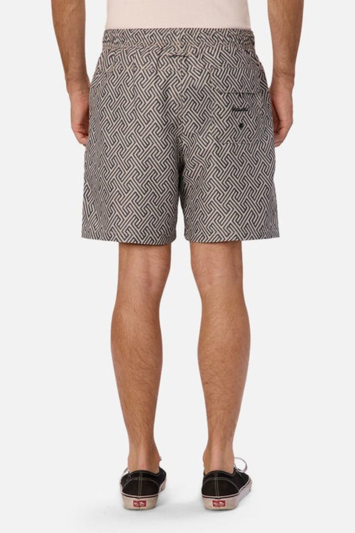 Rear view of a person wearing Industrie The Alvarado Swim Short, featuring geometric patterns, paired with black shoes with red soles—perfect for aquatic leisure. The quick-drying fabric makes them ideal for any adventure, standing out vividly against the plain white background.