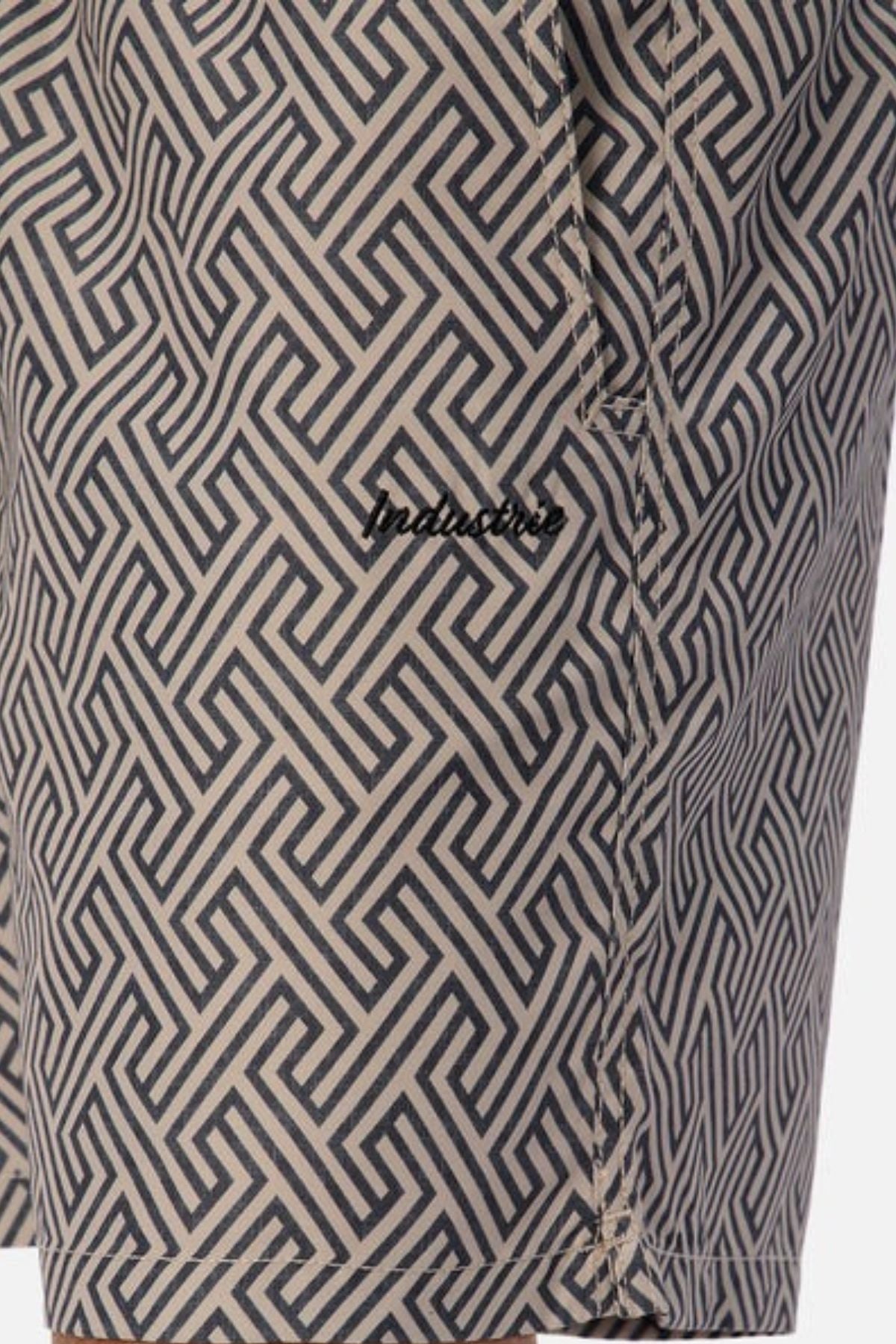 Close-up of fabric with a geometric Greek key pattern in black and beige, ideal for aquatic leisure. The quick-drying material is perfect for fans of the Industrie The Alvarado Swim Short and features a small stitched logo reading "industrie.