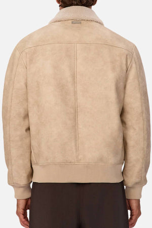 A person with short hair is shown from the back wearing the Industrie The Artem Flight Jacket, a light beige suede bomber featuring a ribbed hem, ribbed cuffs, soft collar, and paired with dark pants.
