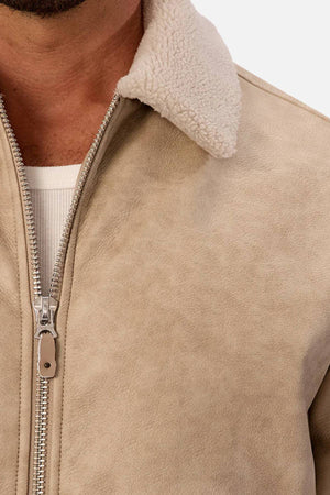 Close-up of a person wearing the Industrie The Artem Flight Jacket in light beige PU leather with a Sherpa-look collar, showing off its rich texture and zipper detail over a white ribbed shirt.